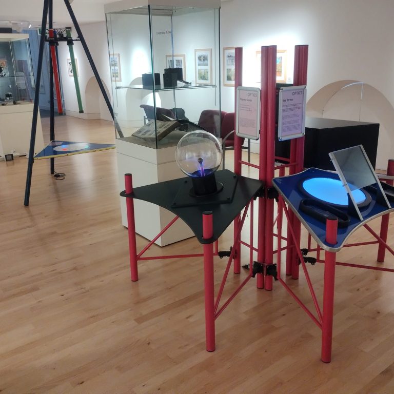 A museum gallery with hands-on interactive science exhibits in the space and photography on the walls.